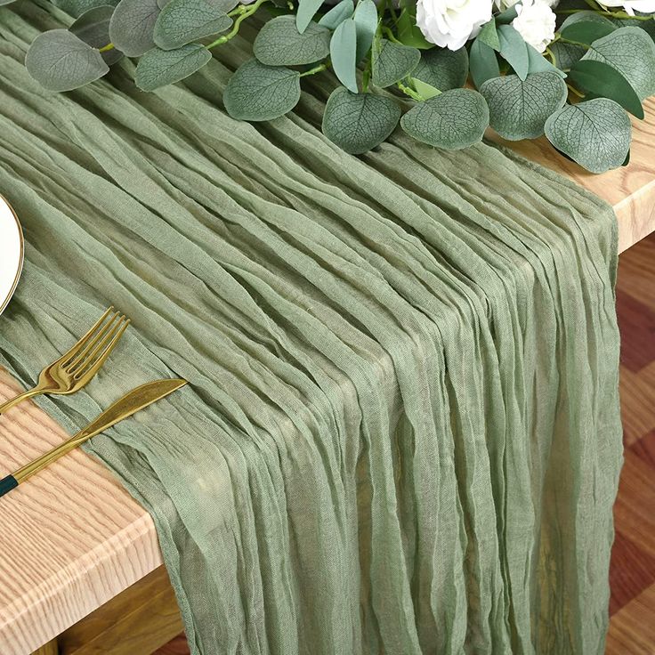 the table is set with green linens and gold utensils, along with white flowers