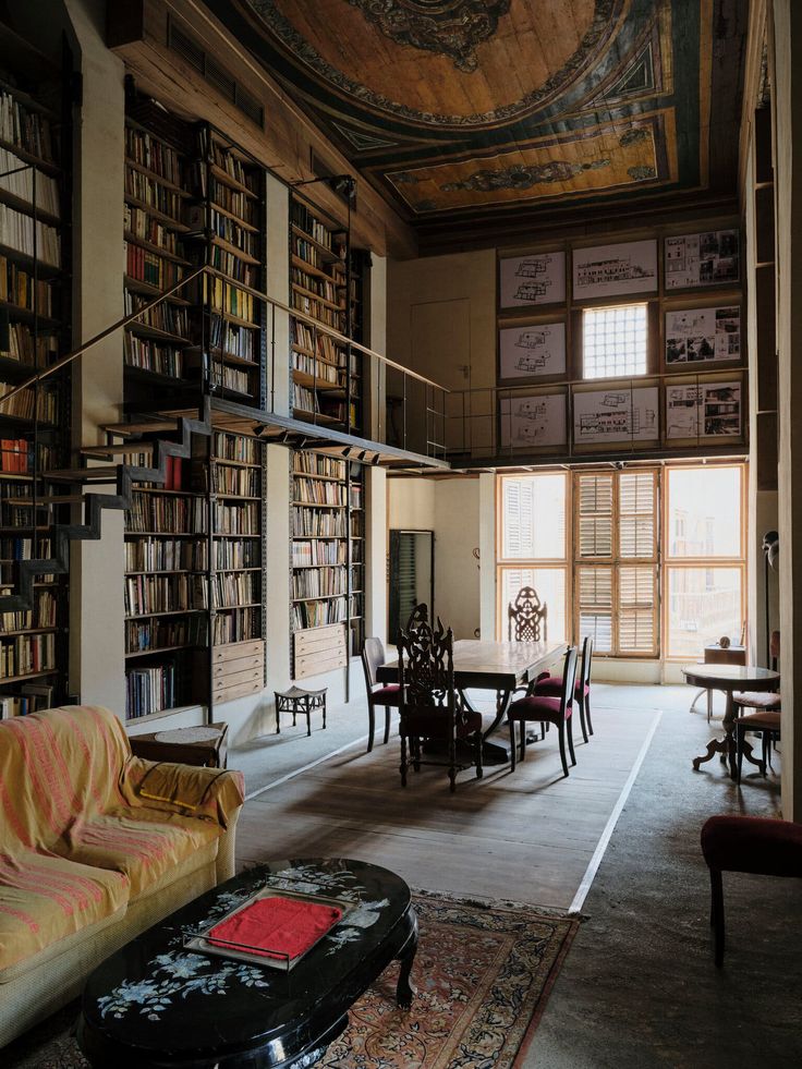 a living room filled with lots of furniture and bookshelves next to a window