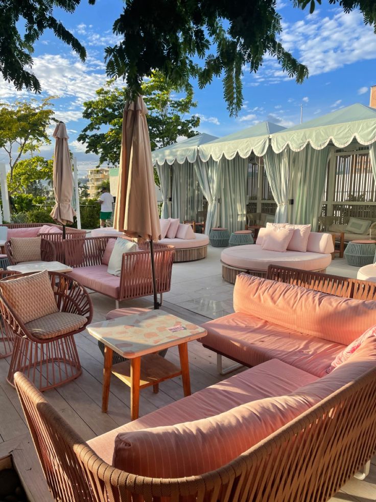 an outdoor seating area with wicker furniture and umbrellas