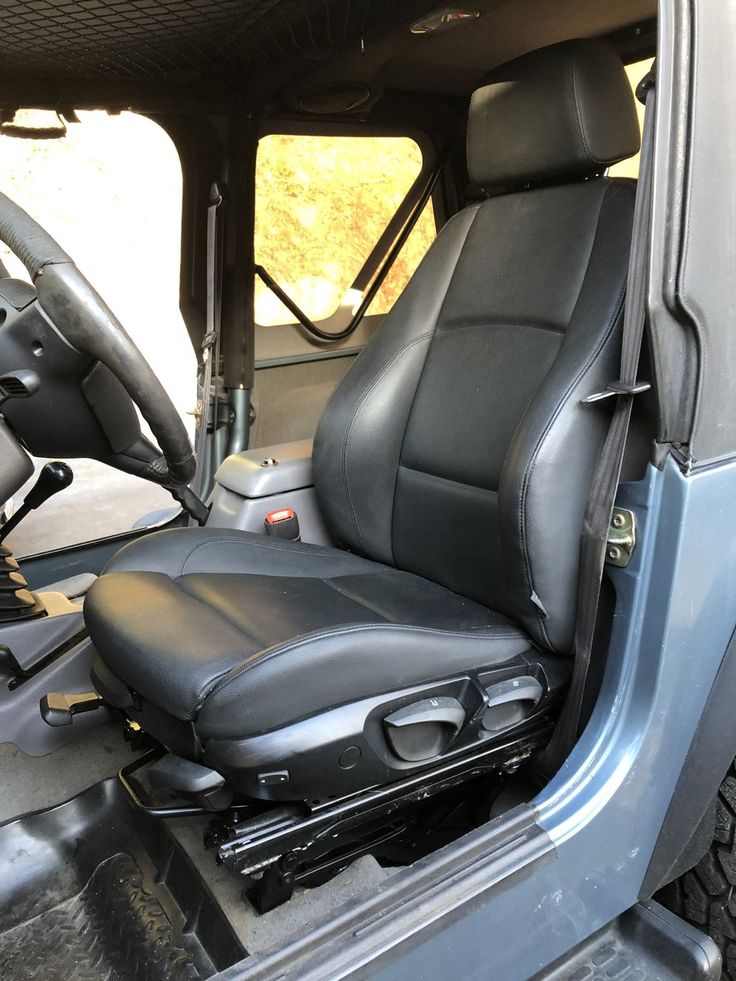 the interior of a truck with black leather seat covers and steering wheel, in front of an open door