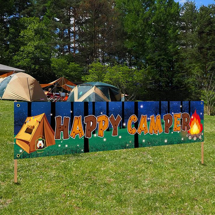 there is a happy camper sign in the grass with tents and trees behind it