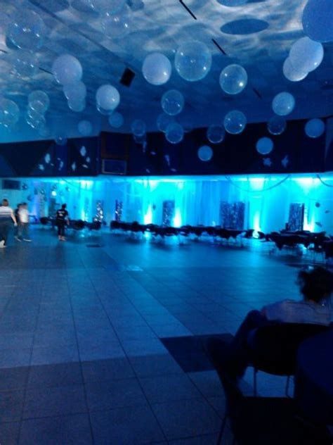 an empty dance floor with blue lights and white balloons hanging from the ceiling above it