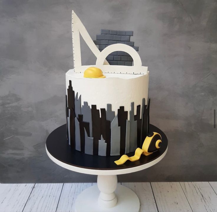 a white and black cake sitting on top of a table next to a gray wall