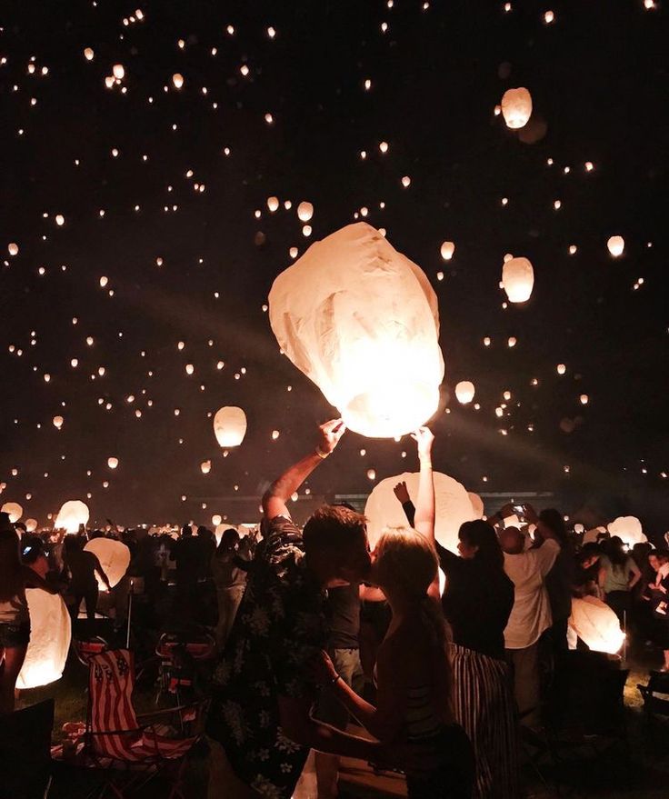 people releasing lanterns into the sky at night