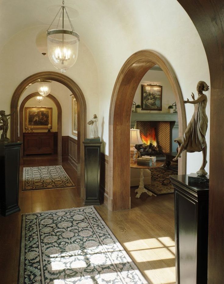 an archway leads to the living room and dining area in this elegant home with wood flooring