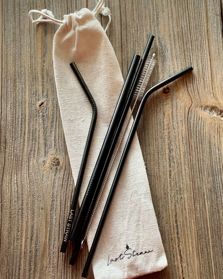 two black straws sitting on top of a cloth bag