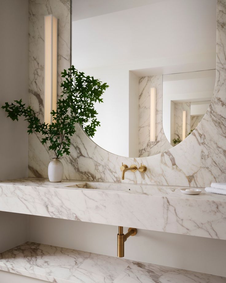 a bathroom with marble counter tops and gold faucets on the sink, along with a mirror