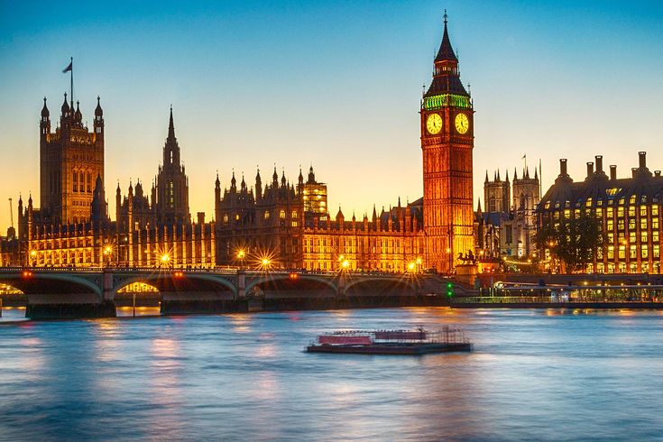 the big ben clock tower towering over the city of london at night with lights reflecting in the water