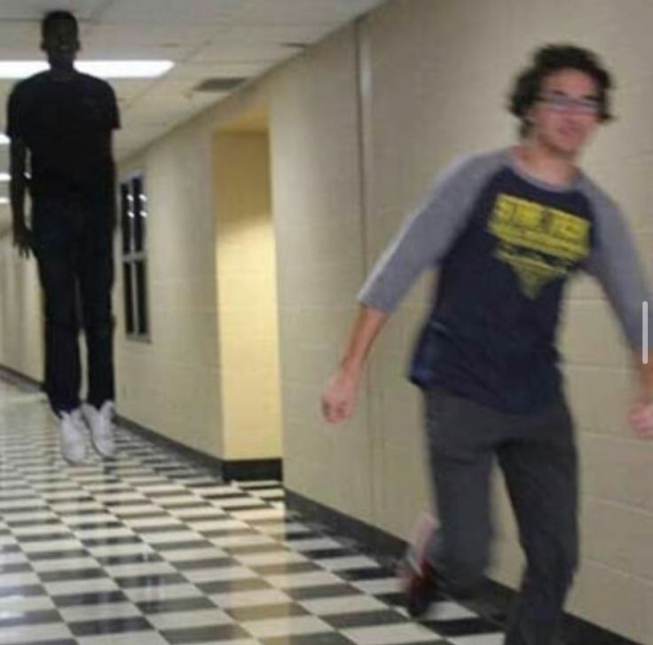 two men walking down a hallway with black and white checkered tile on the floor