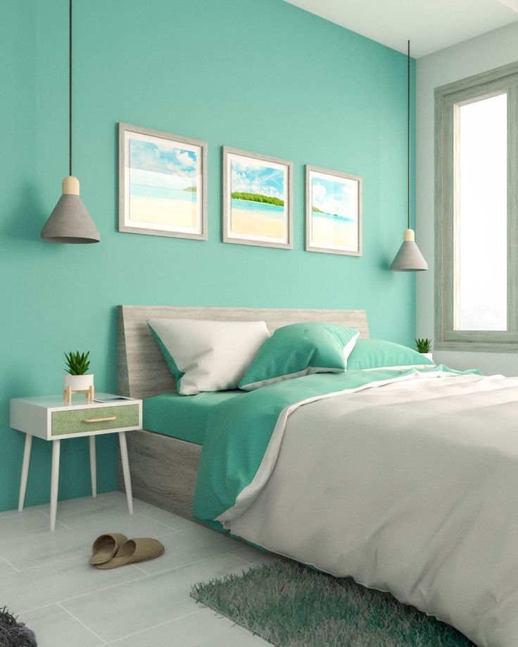 a bedroom painted in aqua and white with two pictures on the wall above the bed