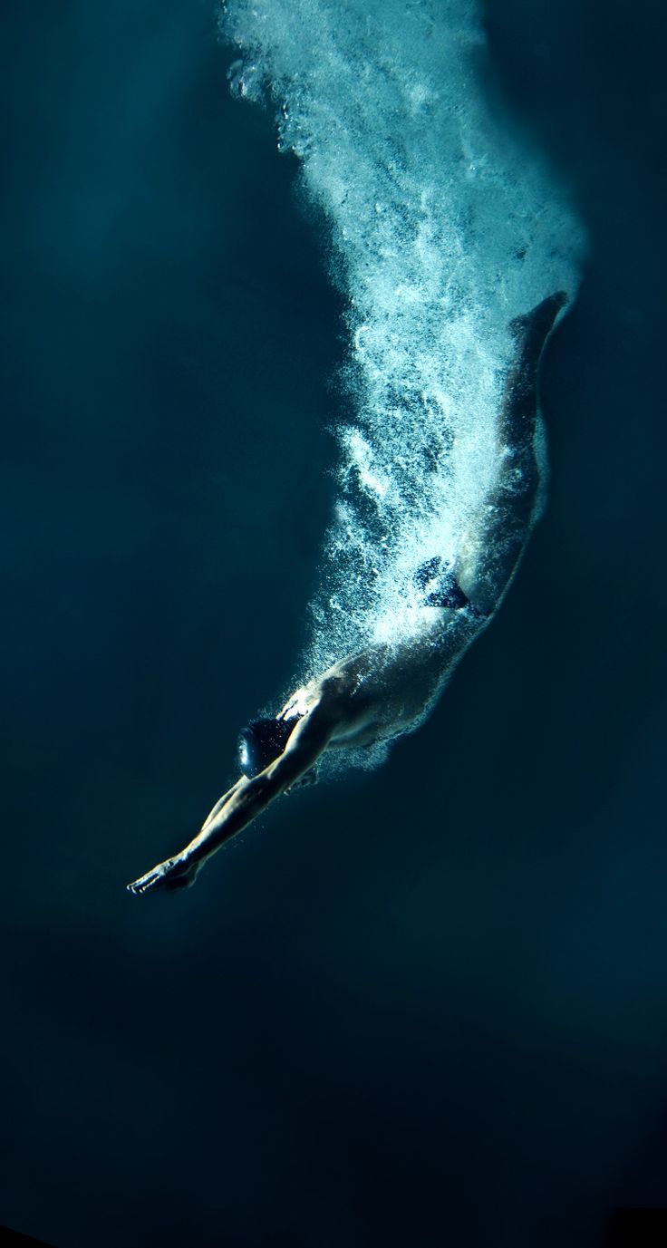 a man swimming in the ocean under a wave