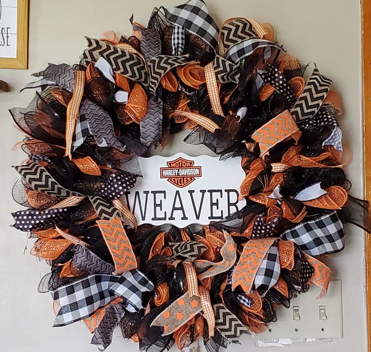 the harley davidson wreath is decorated with black, orange and white mesh ribbons that are hanging on the wall