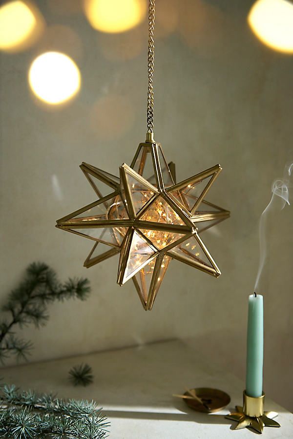 a star ornament hanging from a chain next to a lit candle