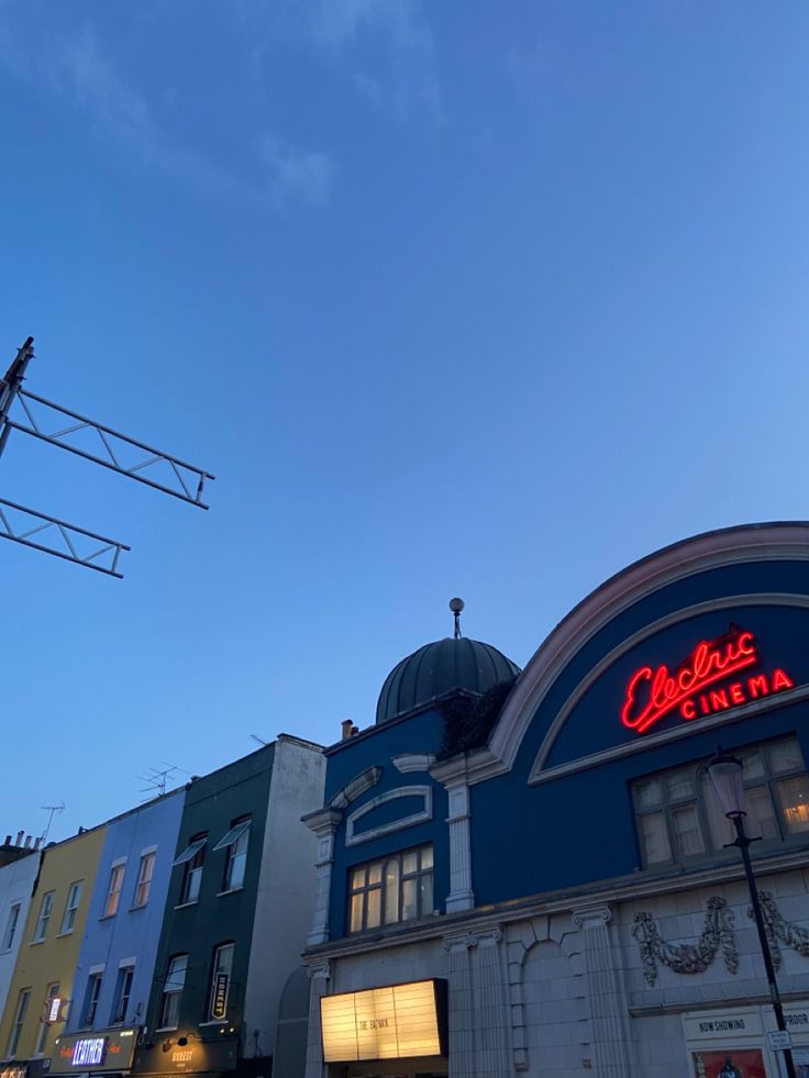 a building with a neon sign on the side of it's roof and some buildings in the background