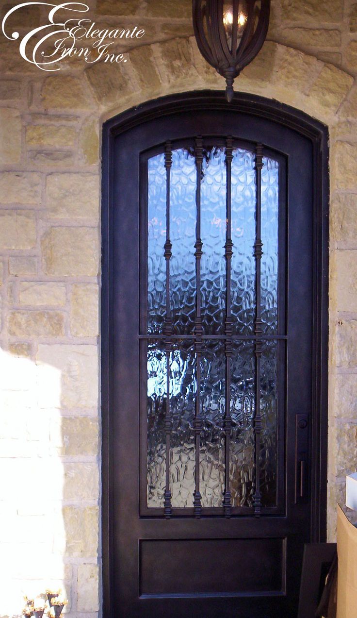 the front door to a home with an iron gate and glass paneled entry door