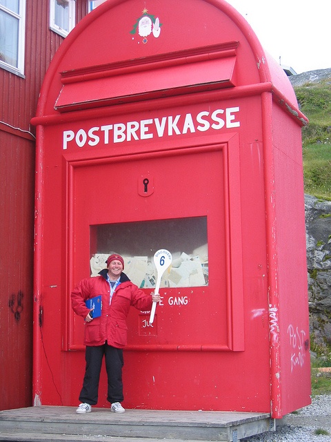 a man standing in front of a red post box