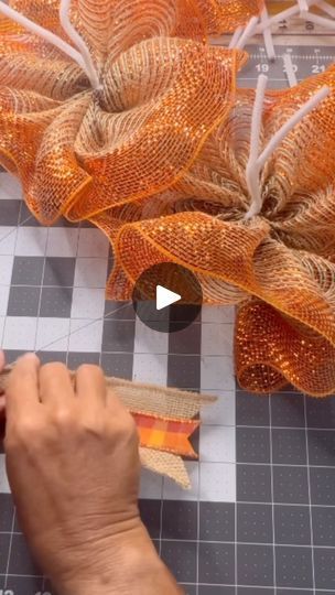 someone is working on some fabric with scissors and tape to make something orange or yellow