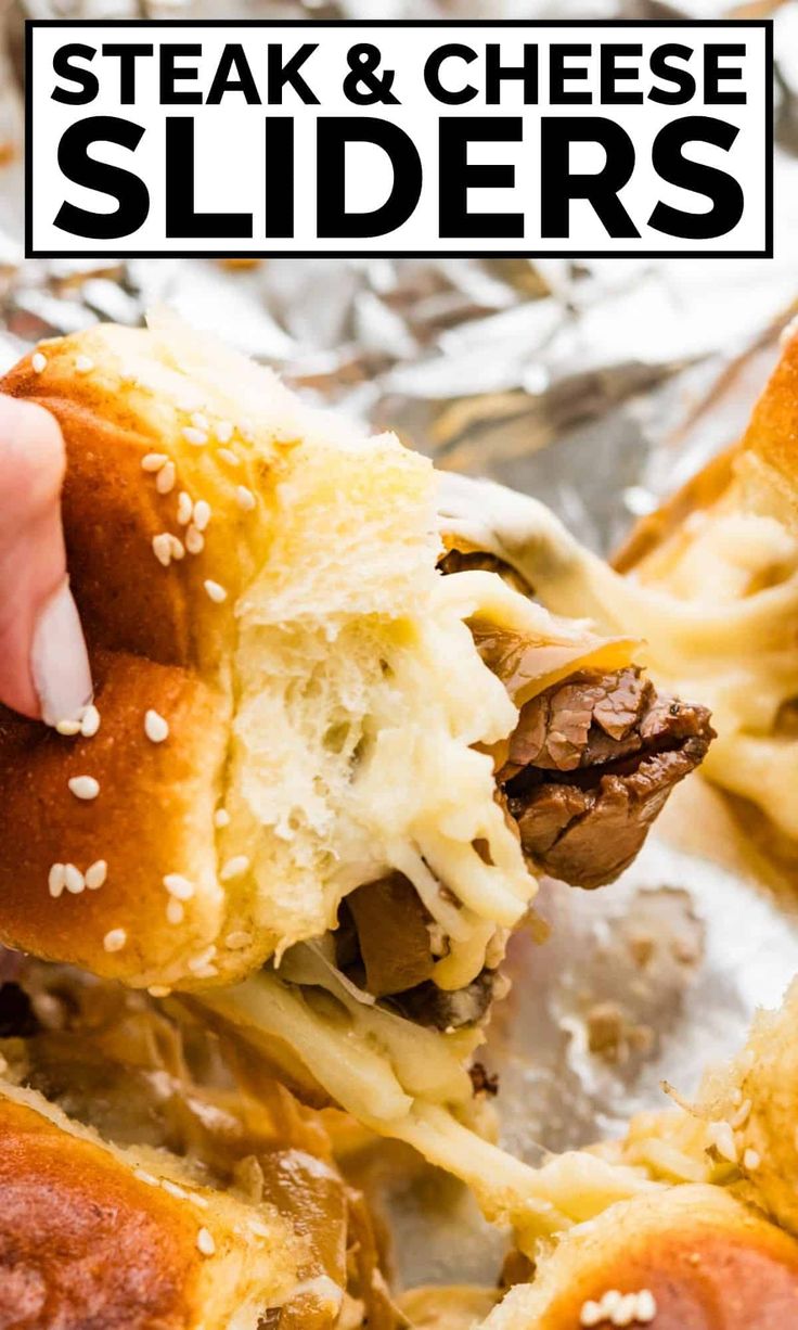 a hand holding a meat and cheese slider over foil with the words steak and cheese sliders on it