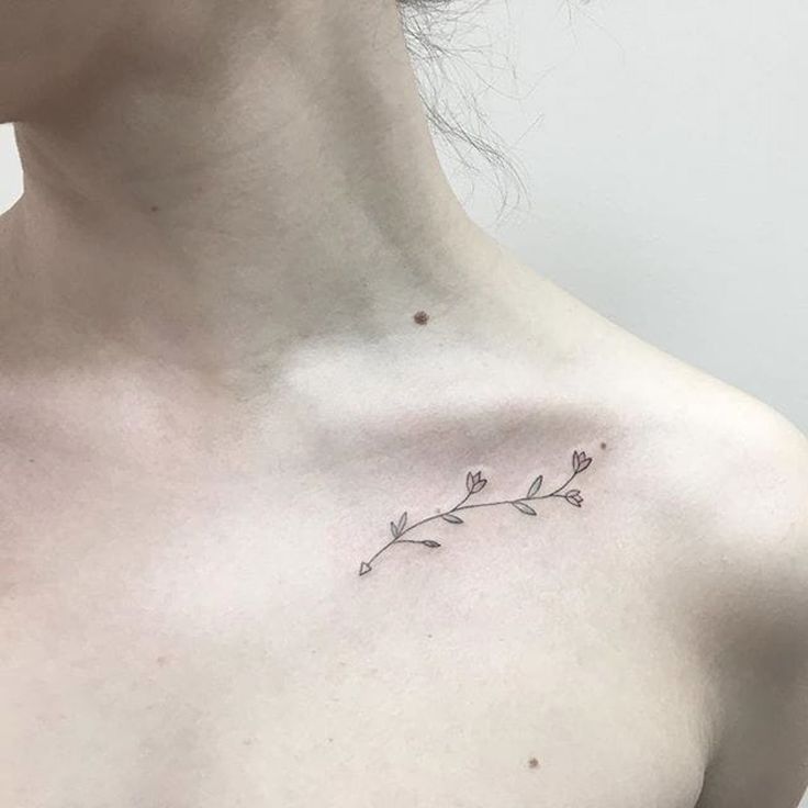 a woman's chest with a small flower tattoo on the left side of her neck