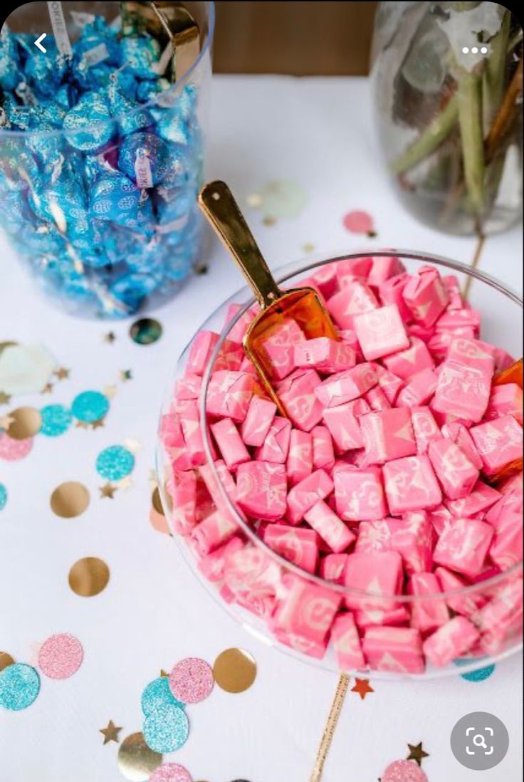 pink and blue candies in a glass bowl on a table with confetti