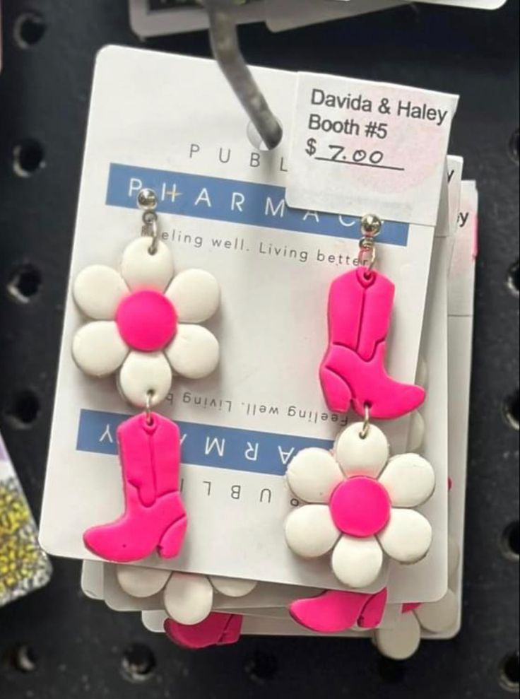 pink and white flower earrings on display at a storefront window, with price tag in the background