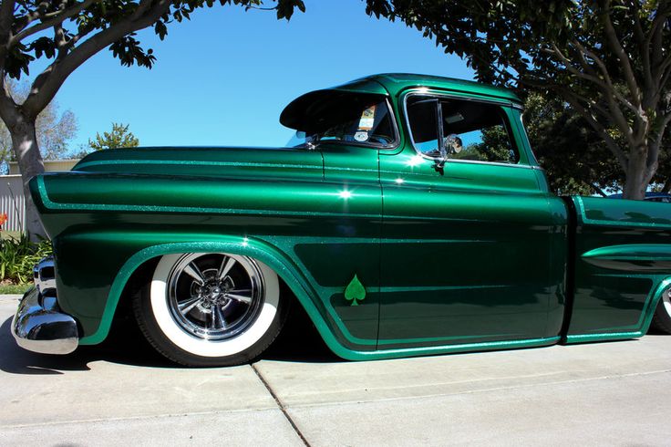 an old green truck parked in front of a tree