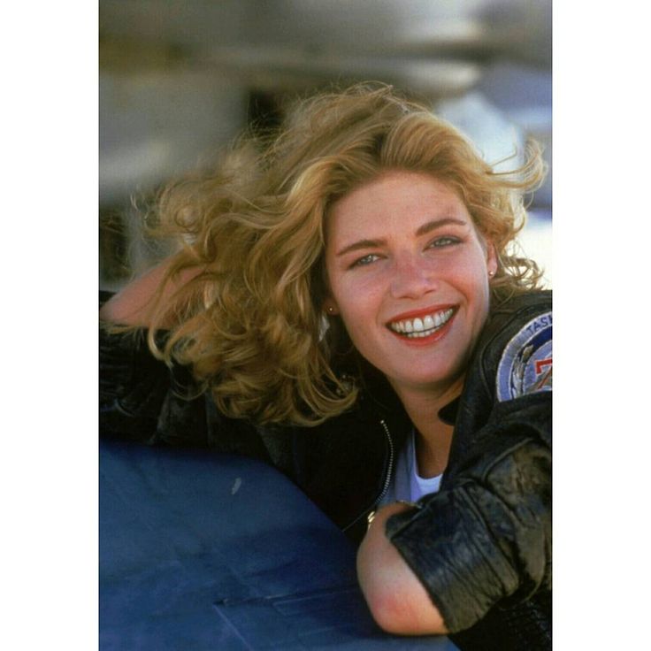 a woman with blonde hair and leather gloves on her arm, smiling at the camera