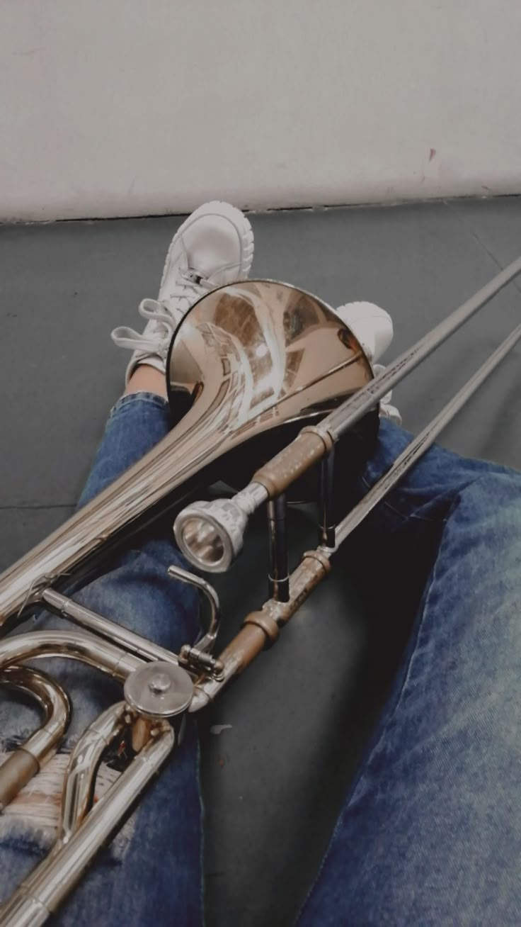 a person sitting on the ground with their feet propped up next to a trombone instrument