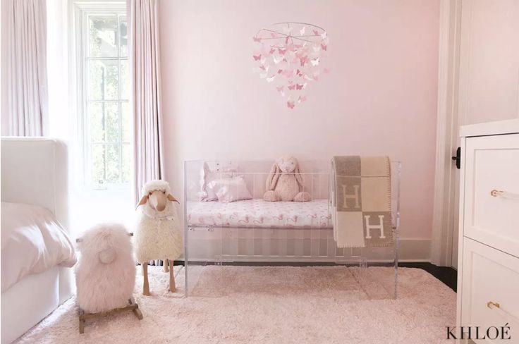 a baby's room with pink walls and white furniture