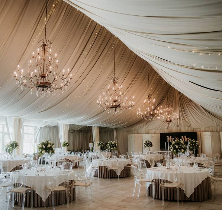 a banquet hall with tables, chairs and chandeliers set up for a formal function