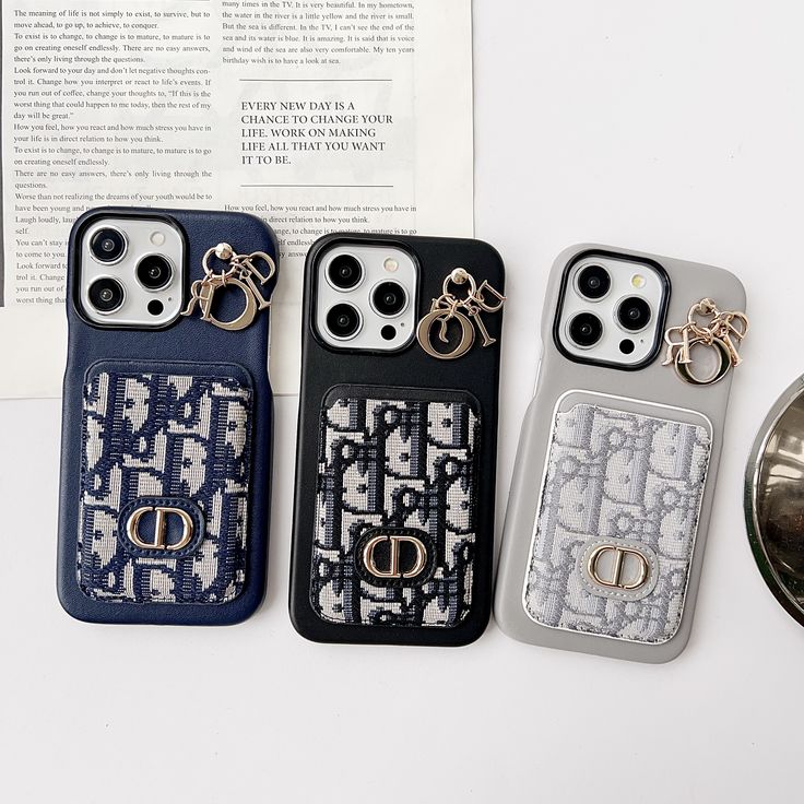 three cell phones sitting next to each other on top of a white table with an open book in the background