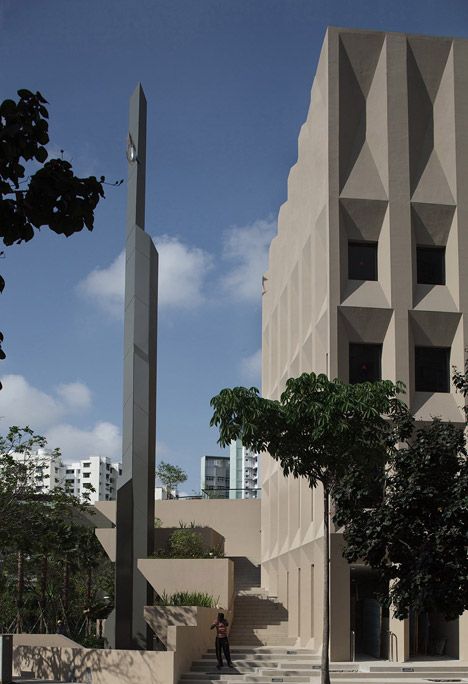 a tall building with stairs leading up to it and a person walking down the street