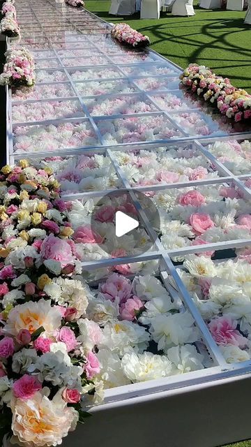 a long table covered in flowers on top of a lush green field with rows of white and pink flowers