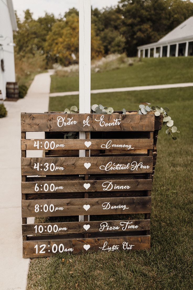 a wooden sign sitting on top of a grass covered field next to a white house