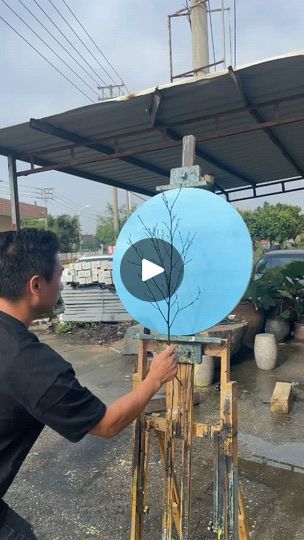 a man is painting a blue object in the middle of an outdoor area with trees