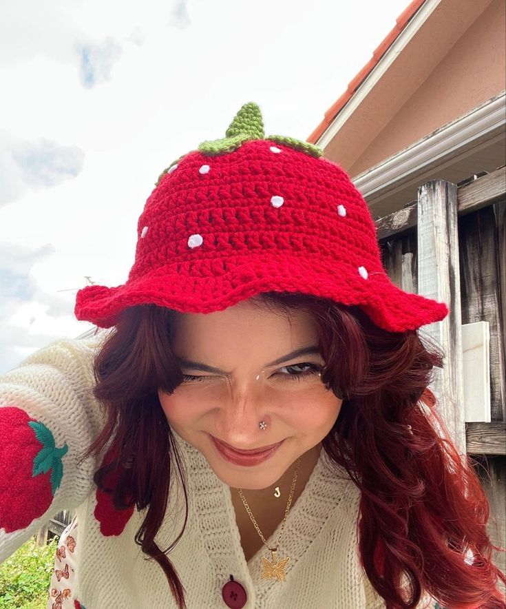 a woman wearing a red crocheted strawberry hat