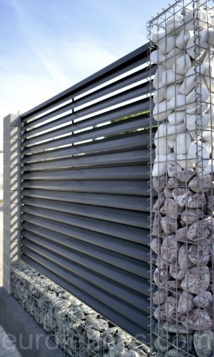 there is a metal fence that has many rocks in it and some are stacked up on top of each other