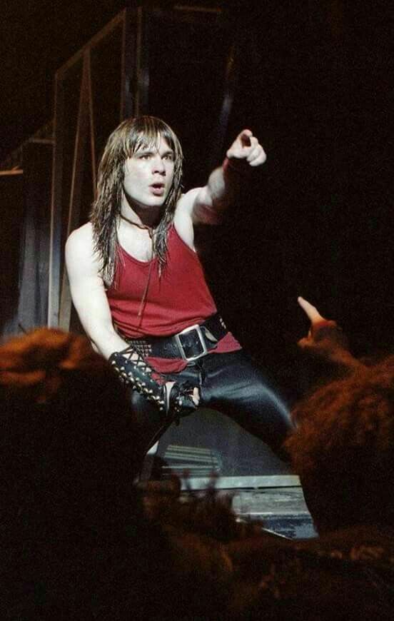 a man with long hair and leather pants is on stage in front of an audience