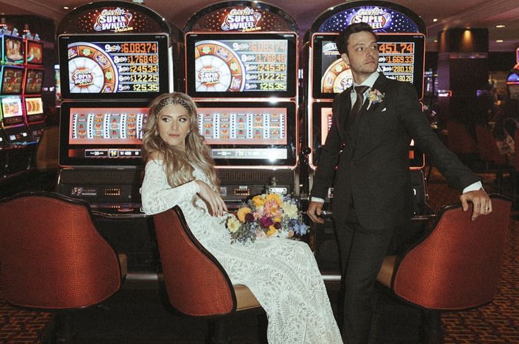 a bride and groom sitting in front of slot machines