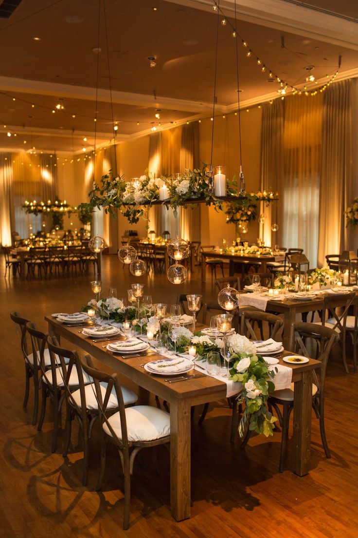 a dining room set up for an event with white and green centerpieces on the tables