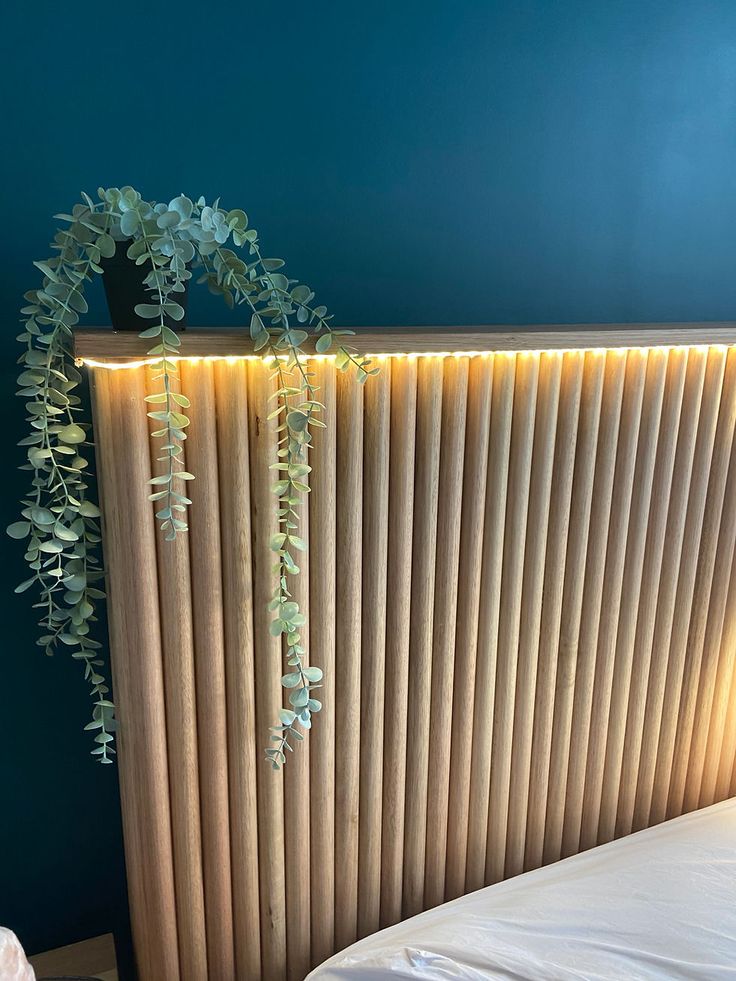 a plant is growing on the side of a wooden paneled wall next to a bed