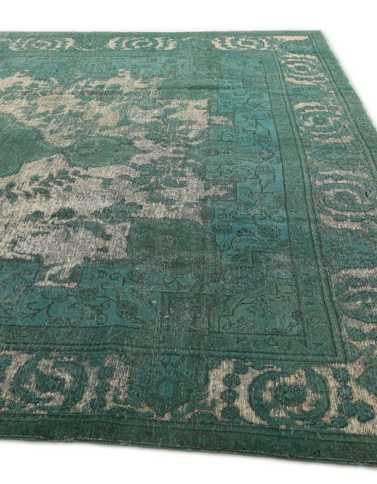 a green rug with an ornate design on the top and bottom, is shown in full view