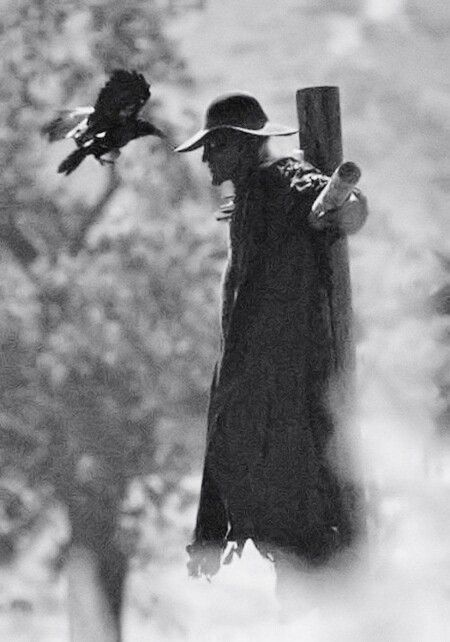 black and white photograph of a man with a bird on his shoulder holding a baseball bat