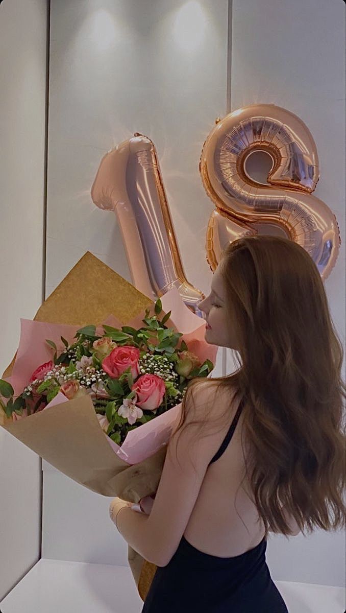 a woman holding a bouquet of flowers in front of the number six balloon and balloons