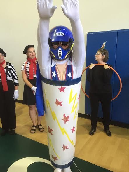 a person in a costume standing next to other people wearing costumes and holding their hands up