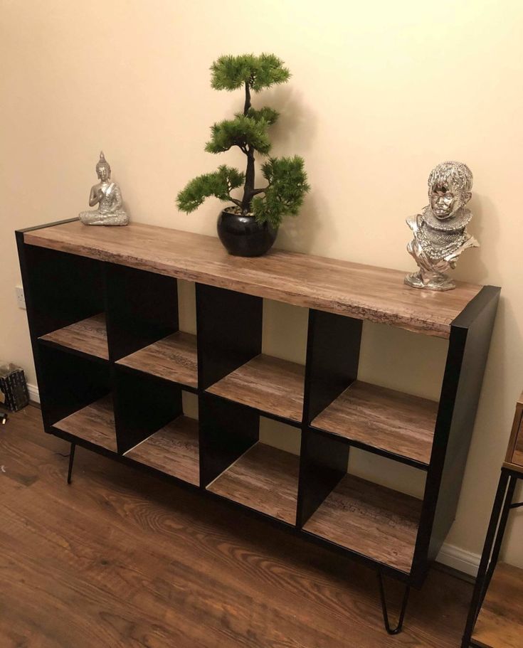 a wooden shelf sitting on top of a hard wood floor next to a table with a potted plant