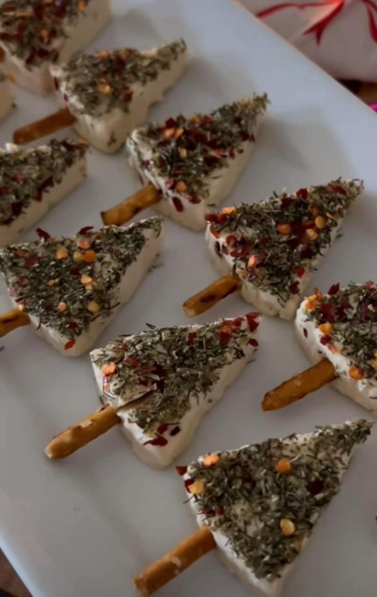 small desserts are arranged on a white platter with pretzels in the shape of christmas trees