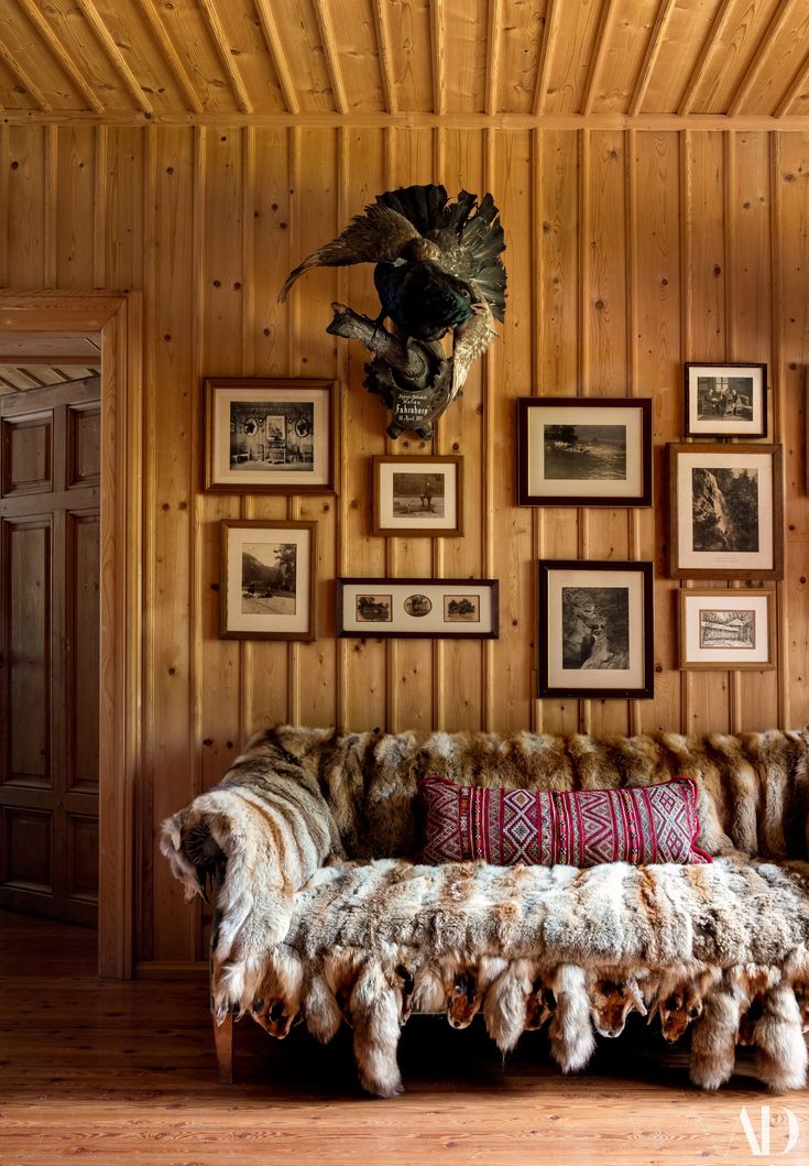 a living room with wood paneling and pictures on the wall, including an old couch