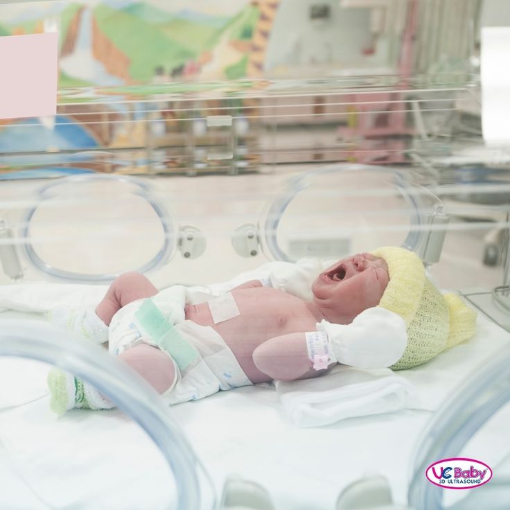 a baby laying on top of a dryer in a room with lots of machines