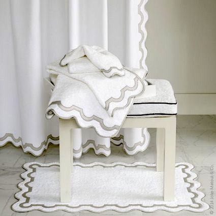 a white blanket sitting on top of a wooden bench next to a window with curtains